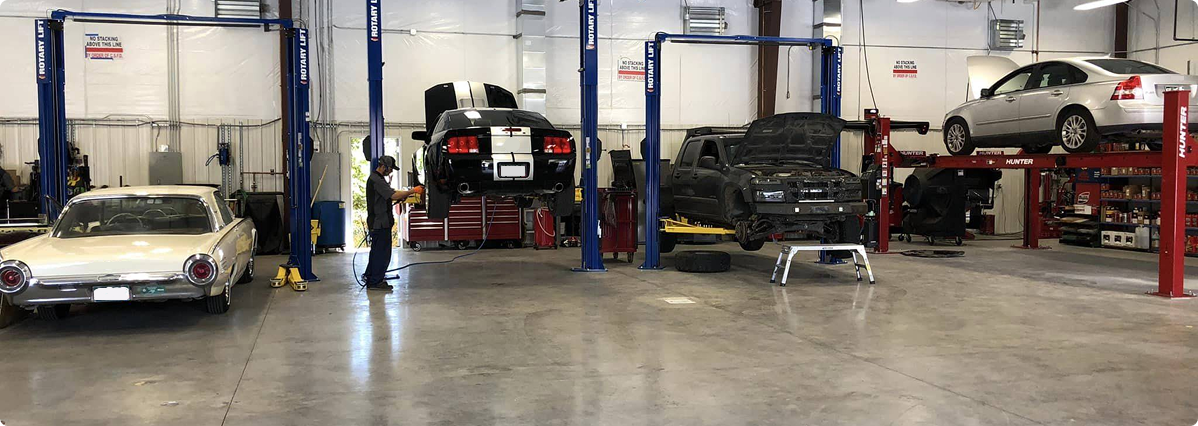 A row of cars are sitting on lifts in a garage. | Patterson Custom Diesel/Automotive