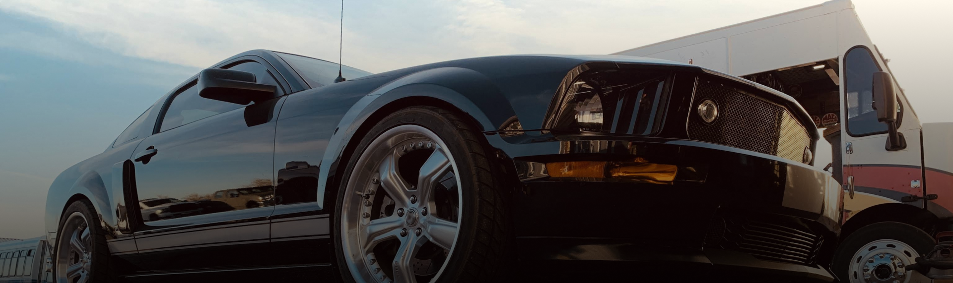 A black sports car is parked in front of a truck. | Patterson Custom Diesel/Automotive
