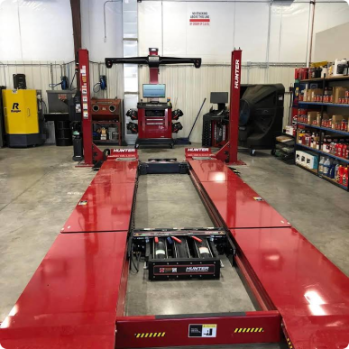 A red alignment machine in a garage with a yellow forklift in the background | Patterson Custom Diesel/Automotive