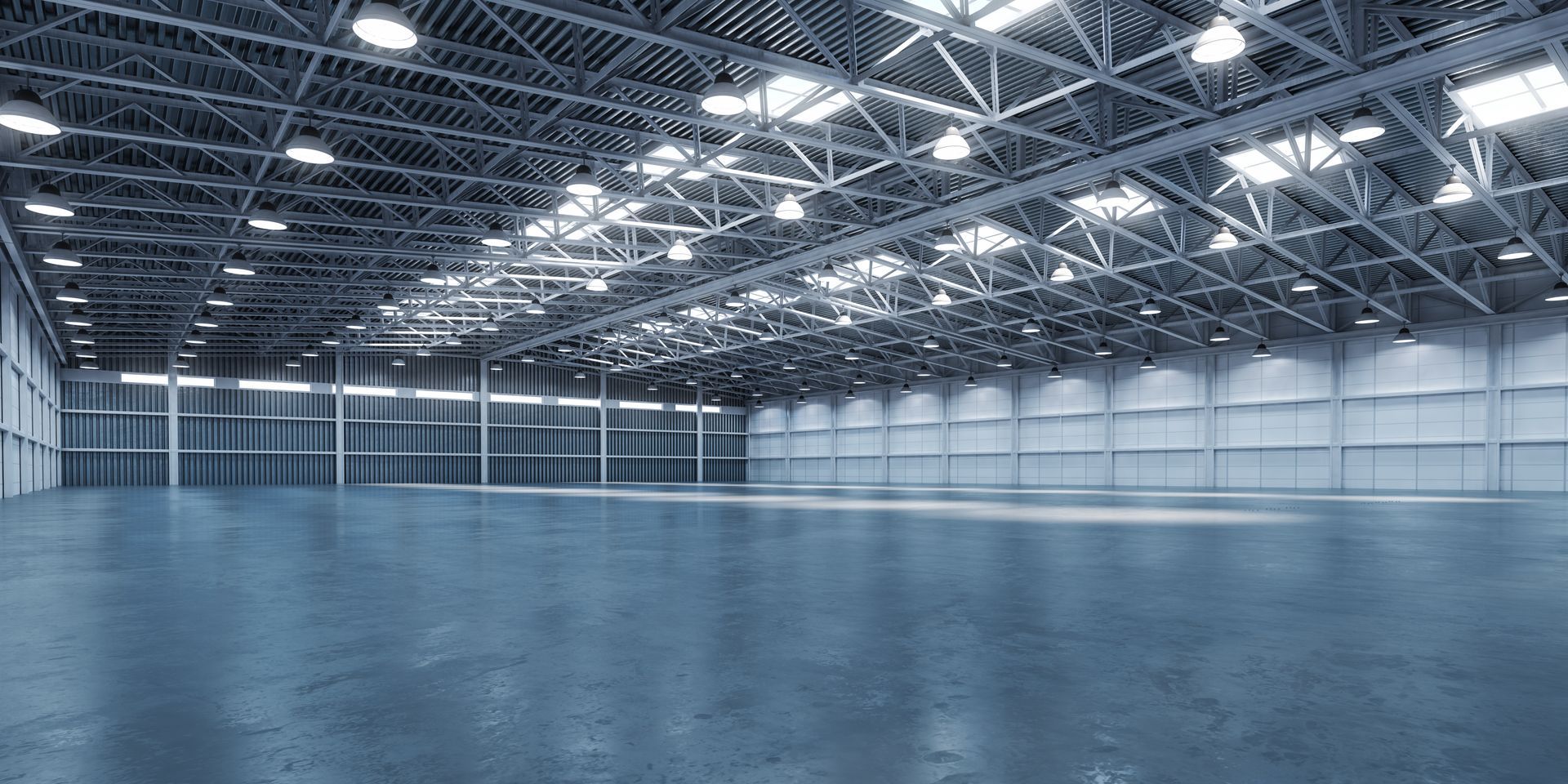 Empty industrial warehouse with high metal trusses and bright overhead lights