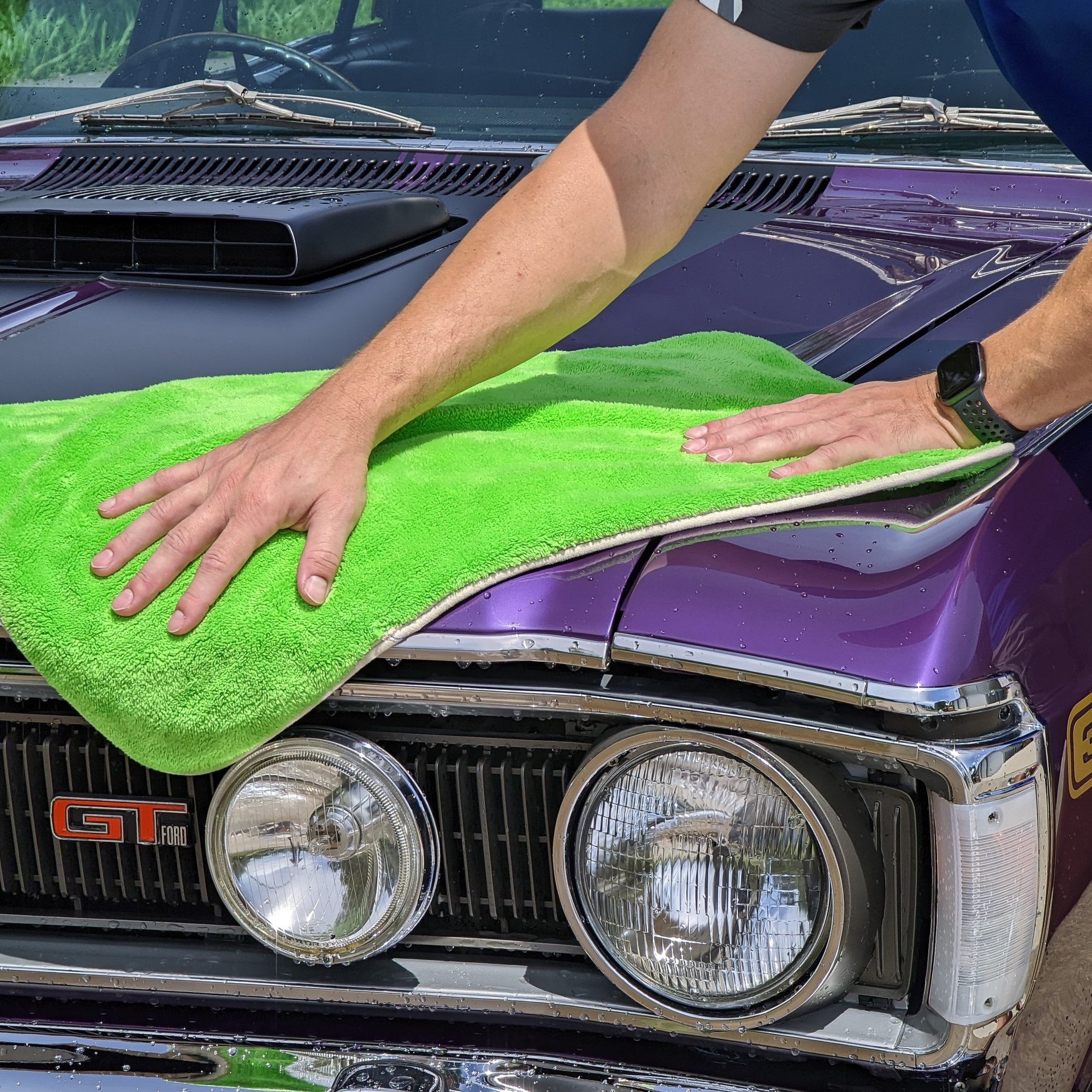 Hands Drying a Purple Classic Car Hood with A Bright Green Towel — Mobile Club Cars Cairns in Earlville, QLD