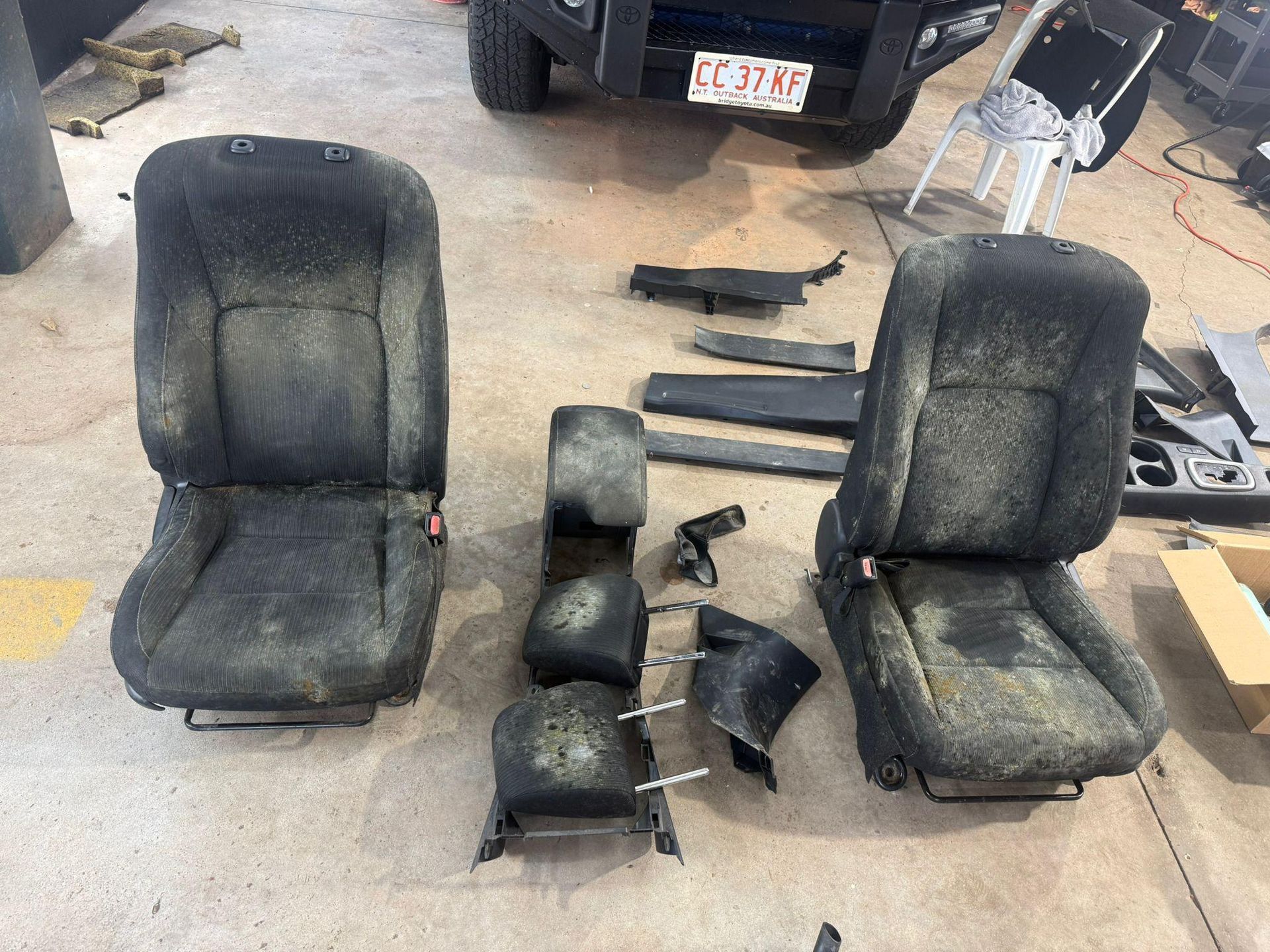 Two Dirty, Dark Grey Car Seats, and Headrests Laid out On a Garage Floor — Mobile Club Cars Cairns in Earlville, QLD