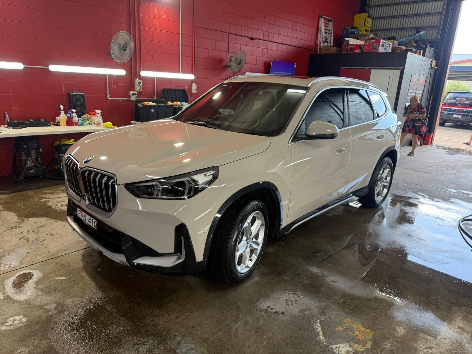 A Beige Bmw Suv Parked Inside A Workshop With Red Walls And A Wet Concrete Floor — Mobile Club Cars Cairns in Earlville, QLD