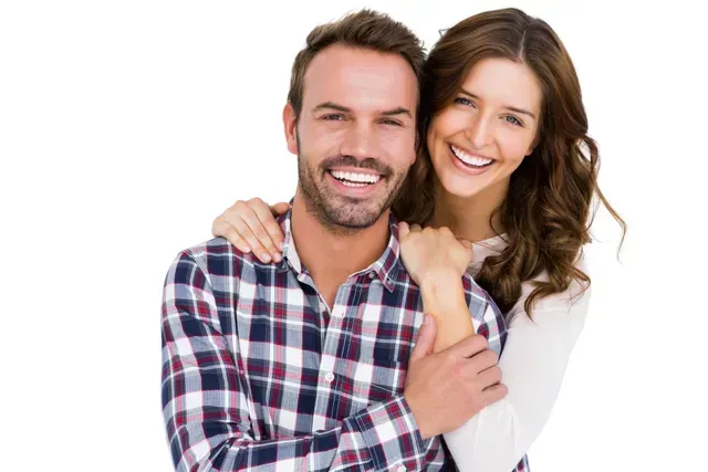 Un homme et une femme se serrent dans leurs bras et sourient à la caméra.