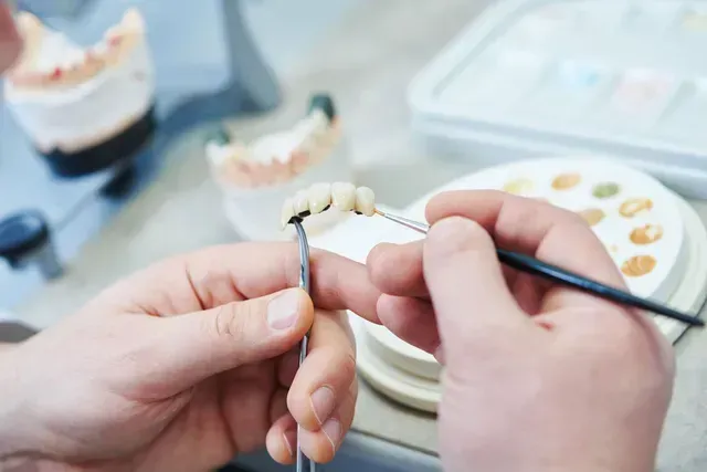Un dentiste travaille sur un modèle de dent avec une brosse.