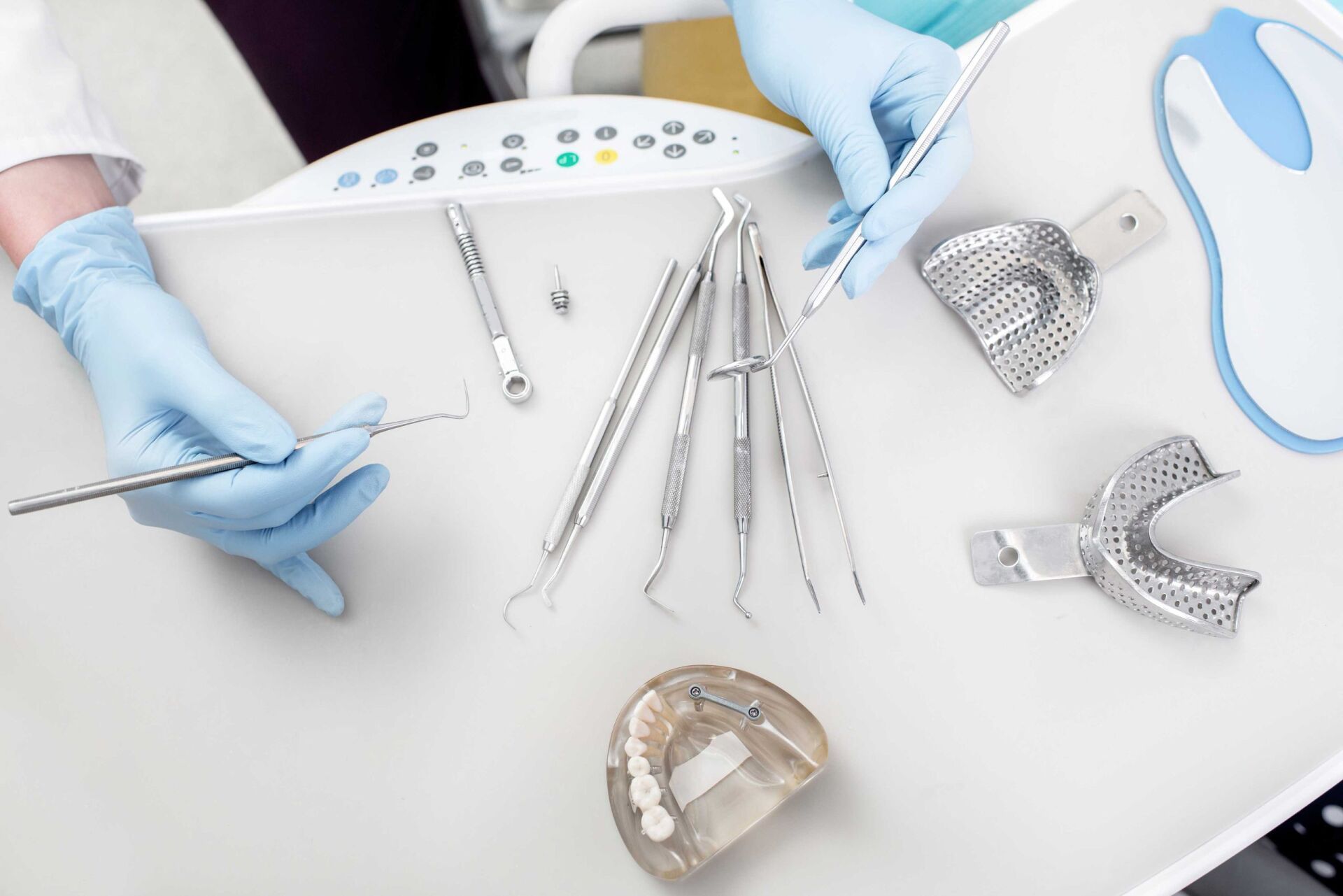 Mains gantées de bleu disposant des instruments dentaires sur un plateau blanc