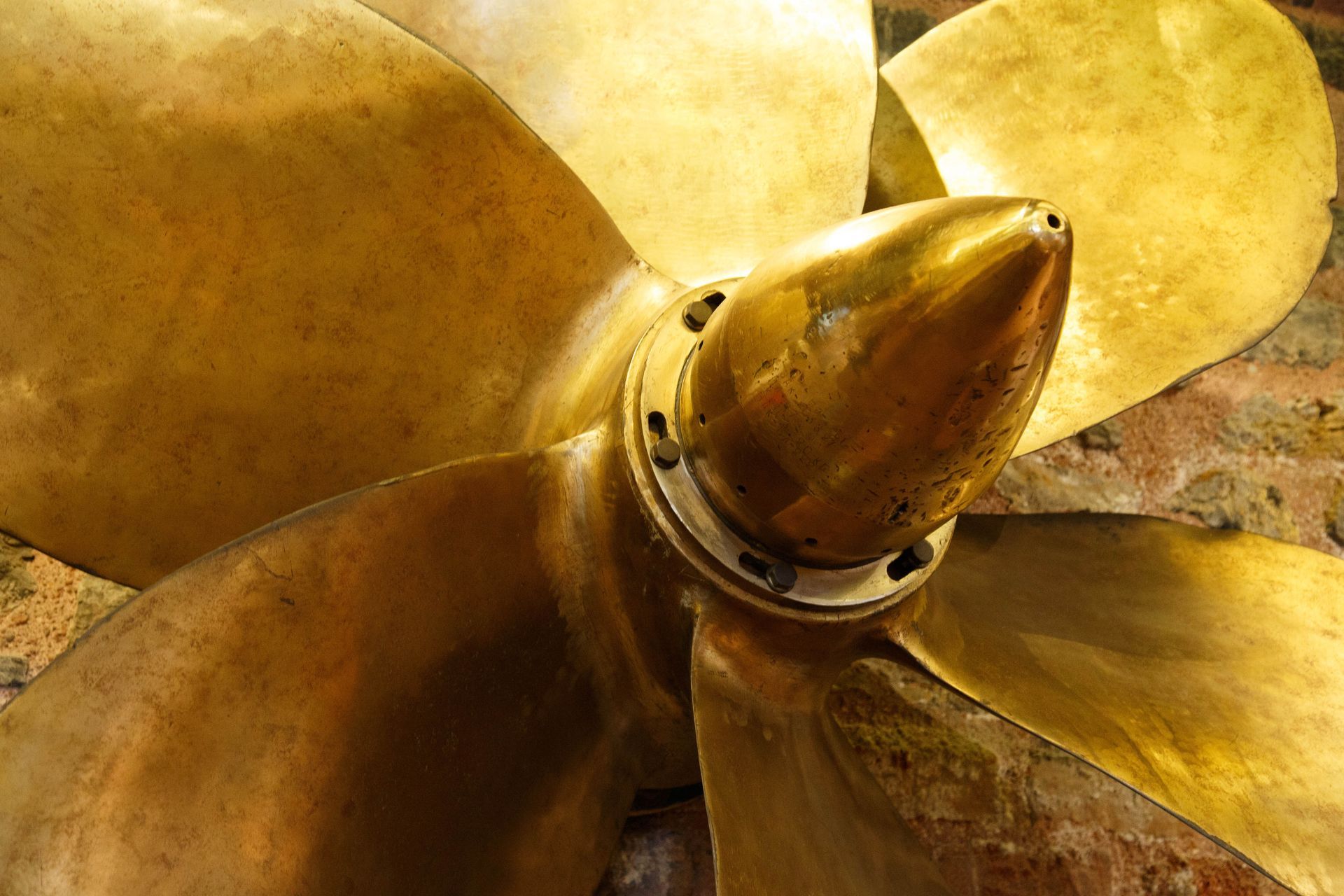 Large golden propeller with four blades, mounted on a base.