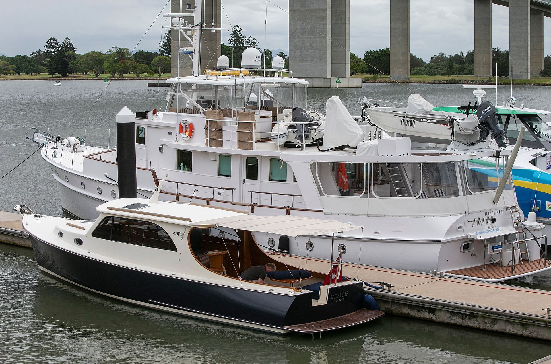 Two white and dark blue boats docked near a bridge, harbor setting.