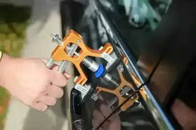 Hand holding an orange-and-black fishing reel mounted on a rod, with blue line visible outdoors