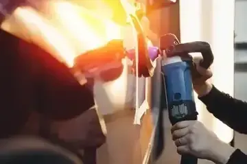 Person using a power tool to cut a metal object, with bright sparks flying indoors