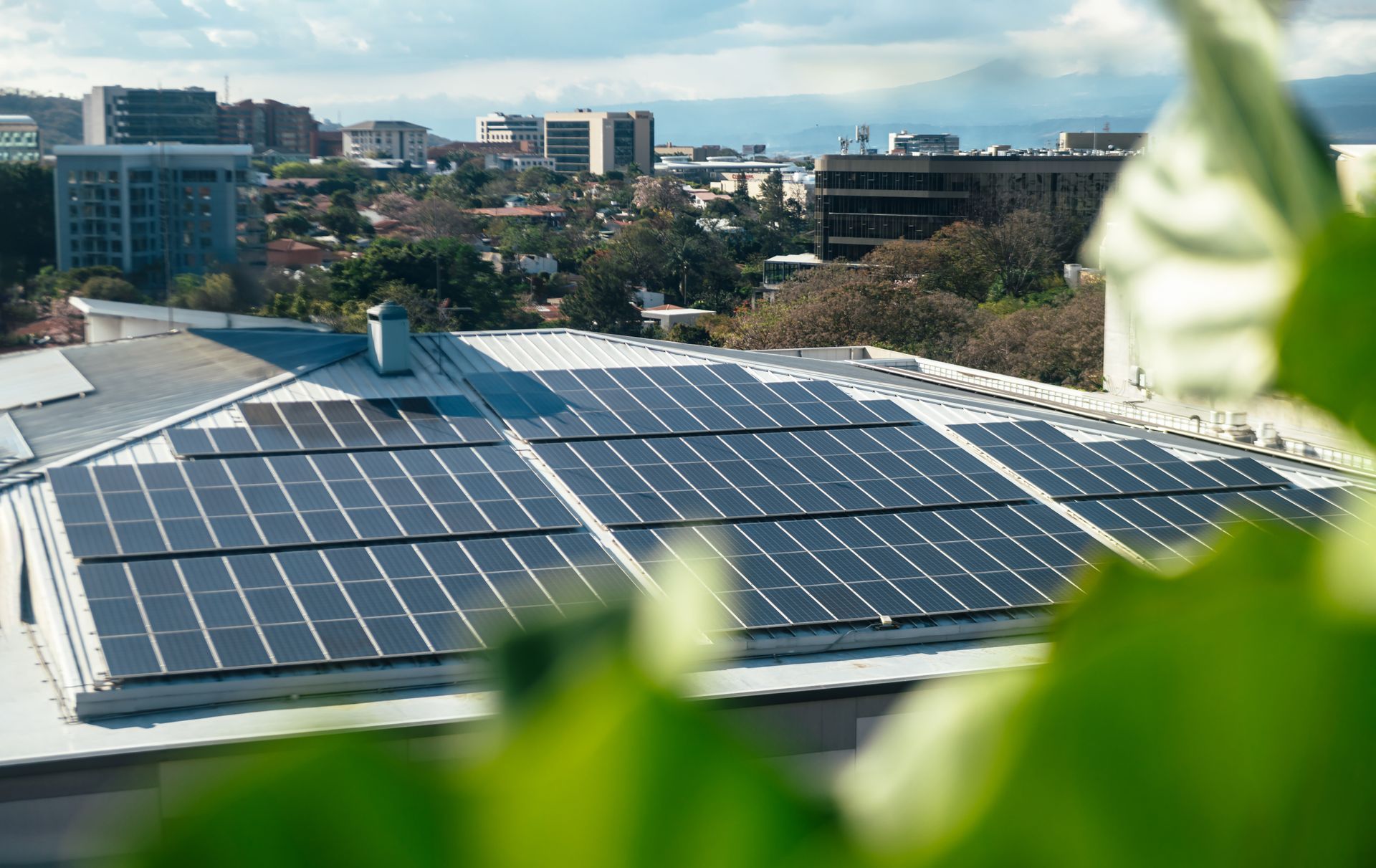 Rooftop solar panels on a building with a city skyline in the background
