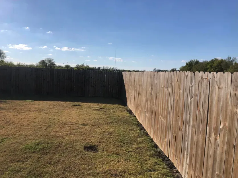 A wooden fence is in the middle of a grassy field.