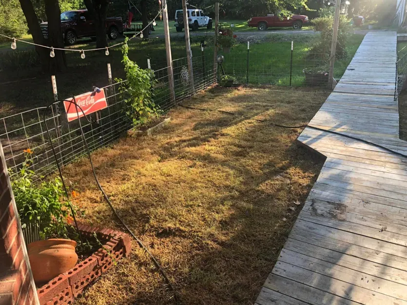 A fenced in yard with a wooden walkway leading to it.