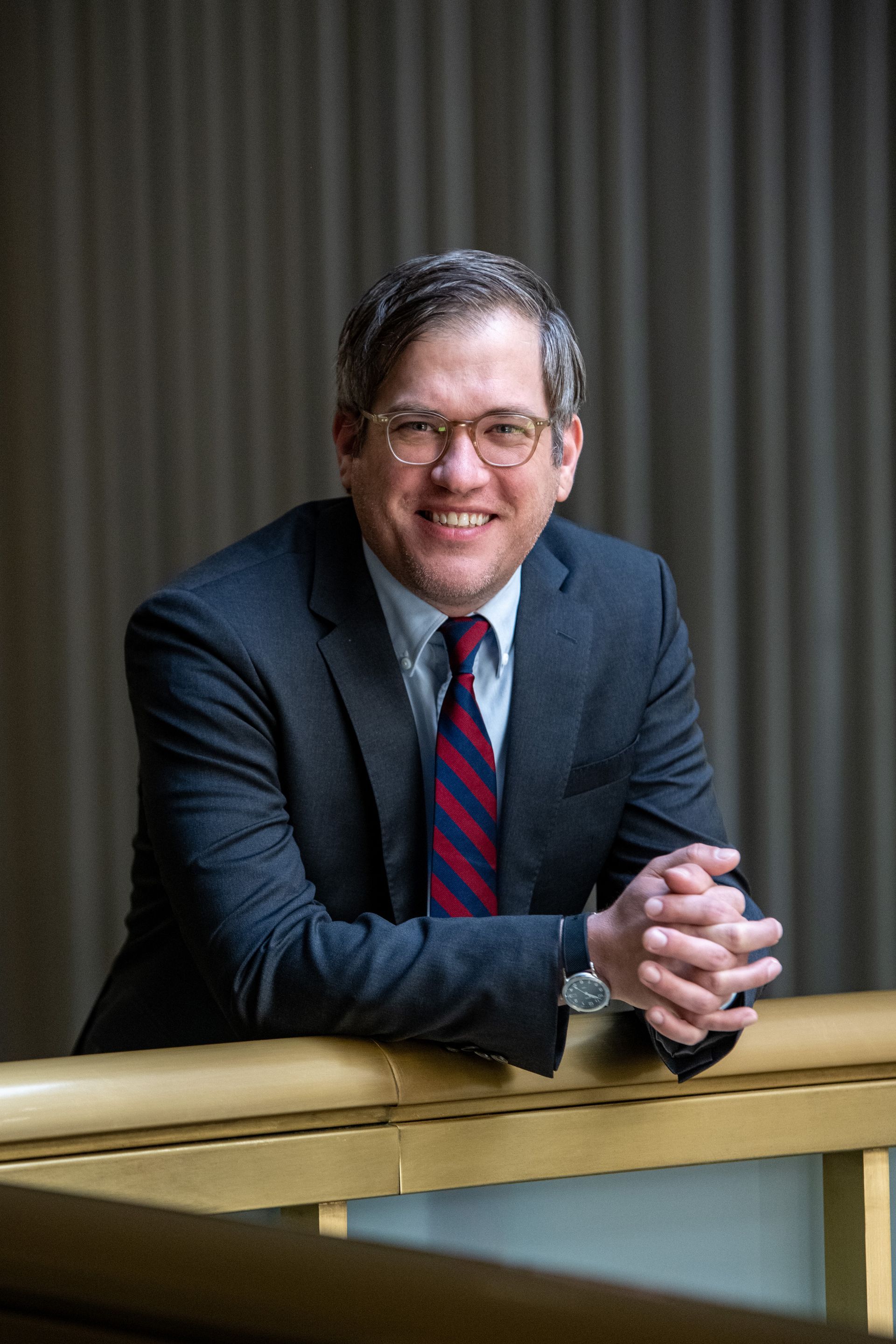 A man in a suit and tie is leaning on a railing.