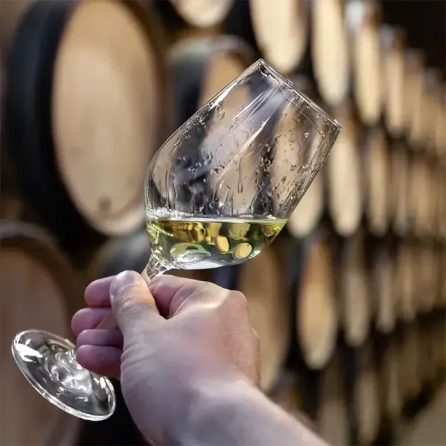 Een persoon houdt een glas wijn vast voor vaten.