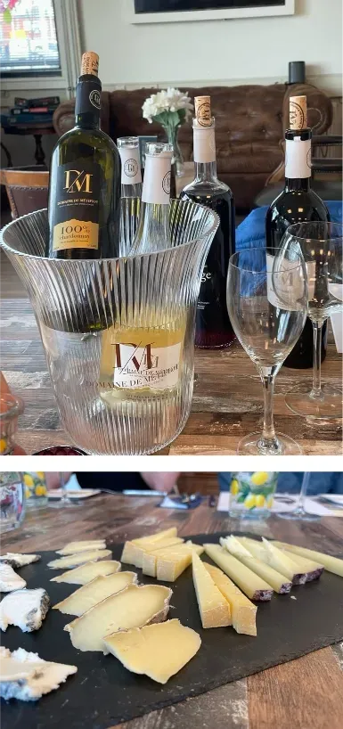 Er staat een fles wijn op tafel, naast een schaal met wijn en kaas.