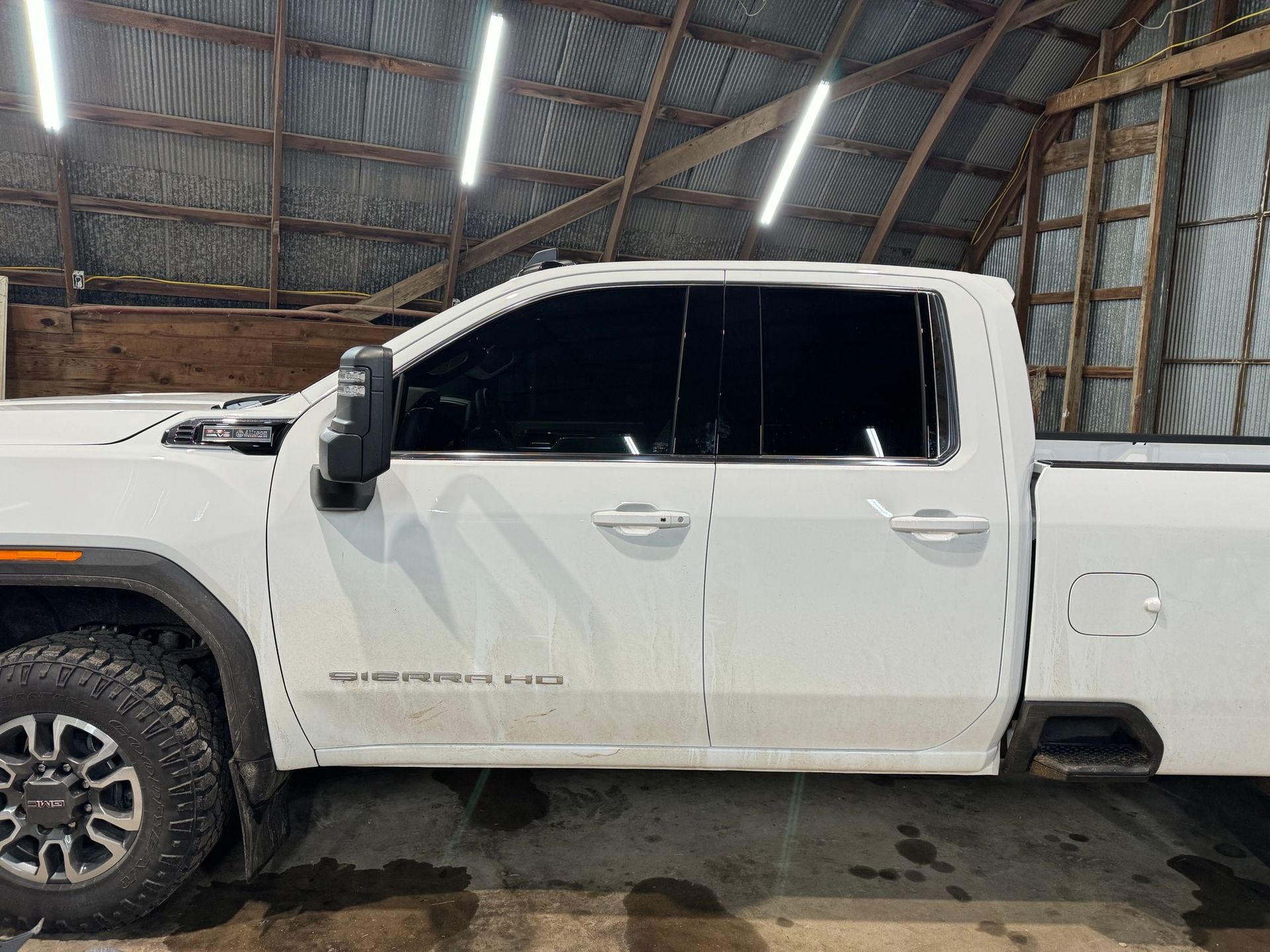 A white pickup truck is parked in a barn.