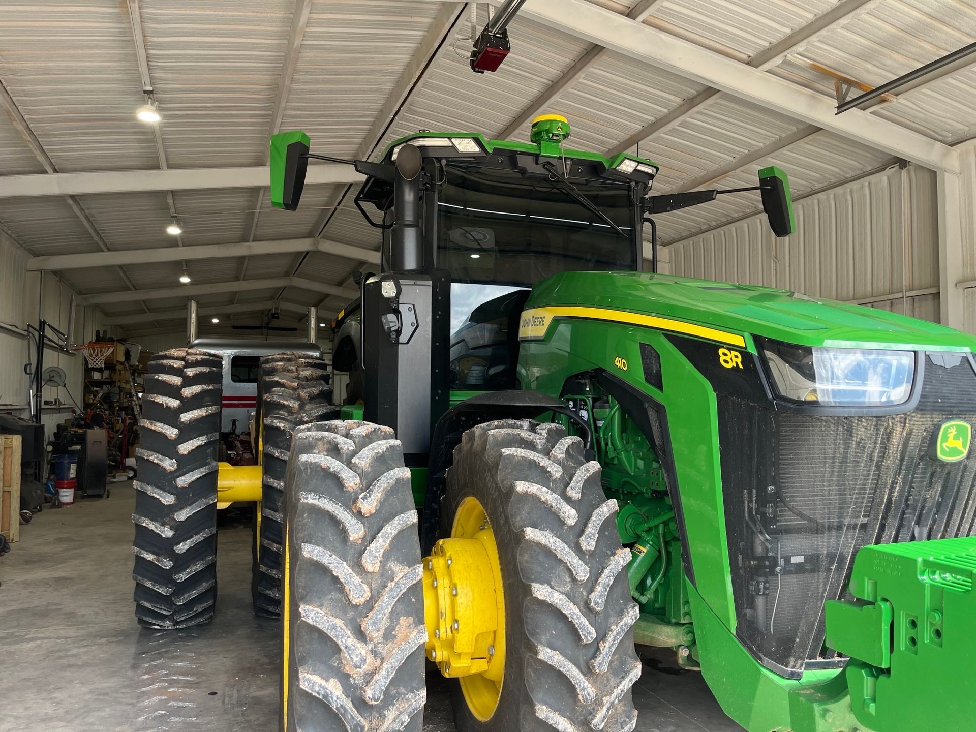 A green and yellow john deere tractor is parked in a garage.