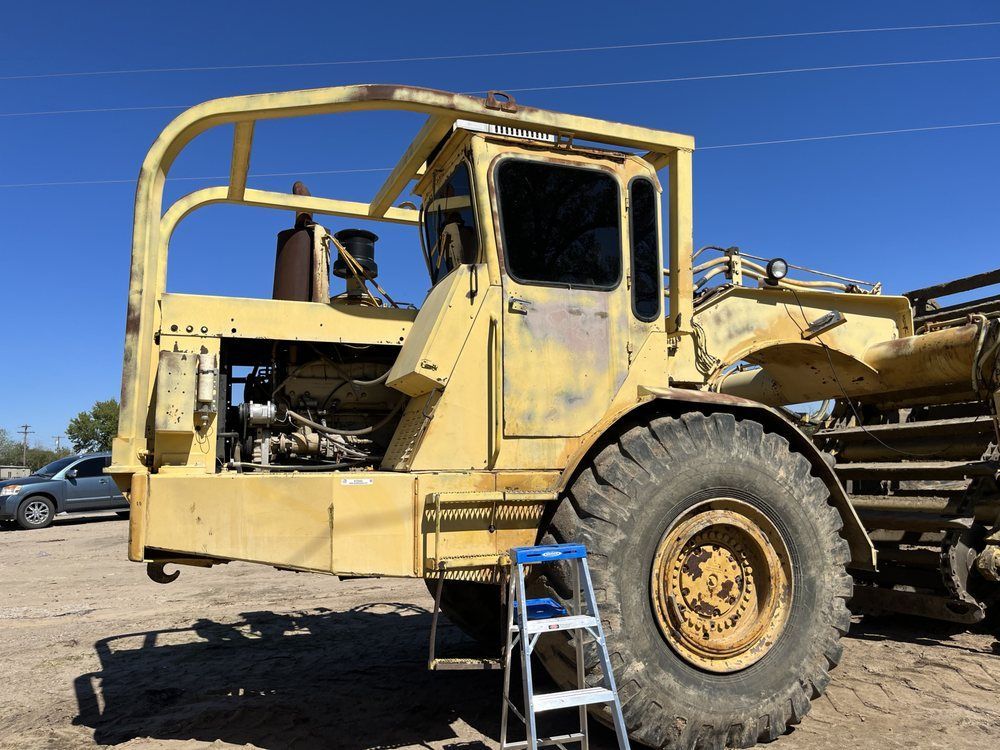 A yellow truck with a ladder leaning against it