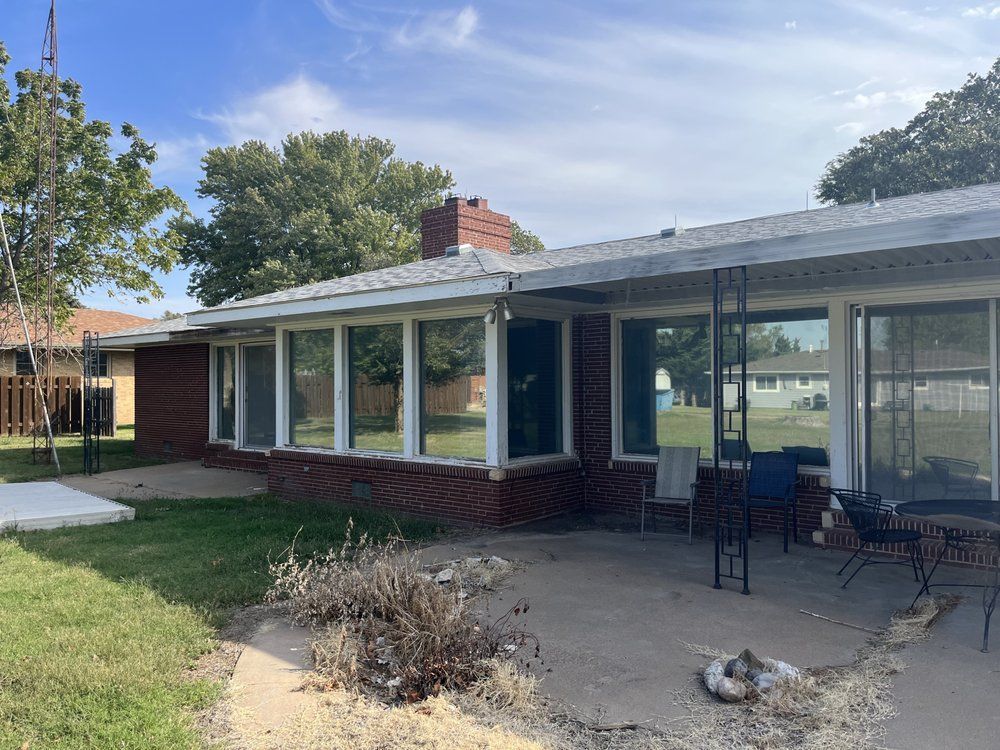 A house with a lot of windows and a patio in front of it.