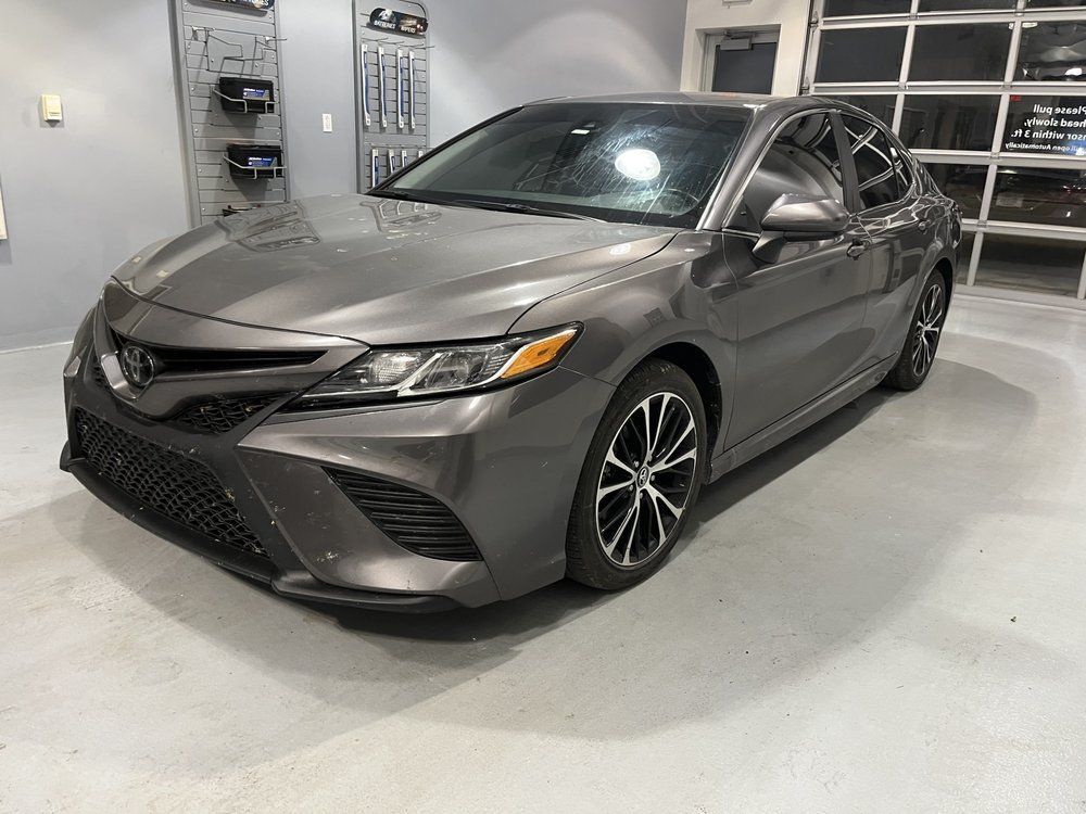 A gray toyota camry is parked in a garage.