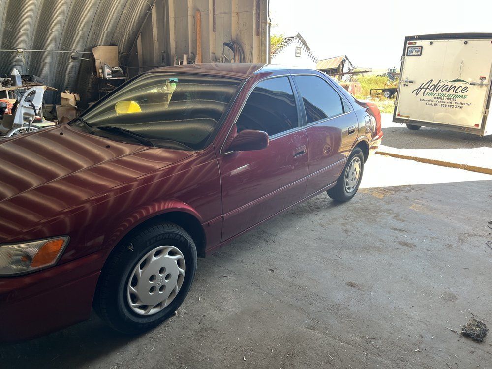 A red car is parked in a garage next to a trailer.