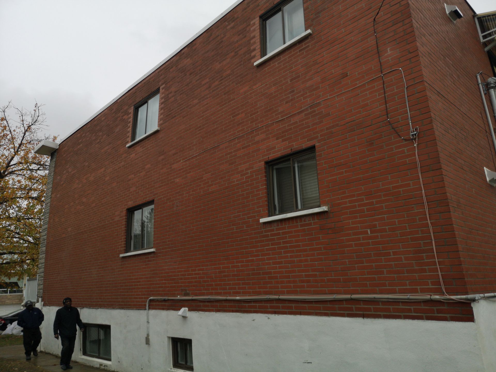 Deux hommes se tiennent devant un grand bâtiment en brique.
