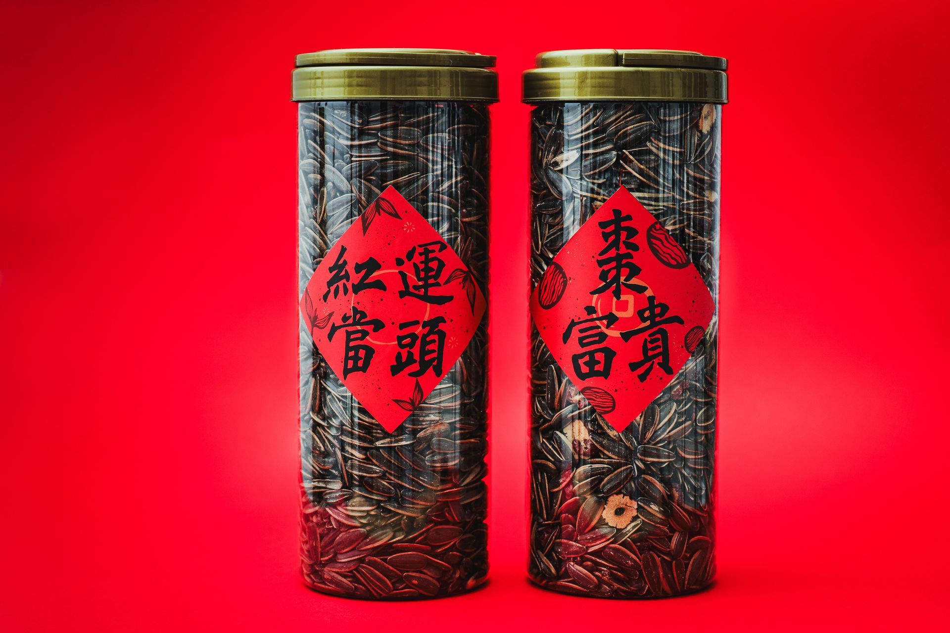 一個木碗裝滿了條紋葵花籽,放在深色石板面上,背景是紅色的布料。