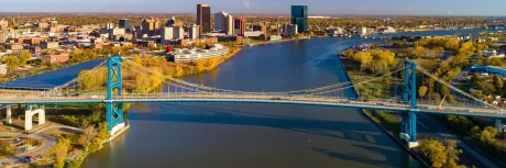 An aerial view of a bridge over a river with a city in the background.