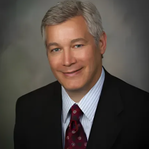 A man in a suit and tie is smiling for the camera