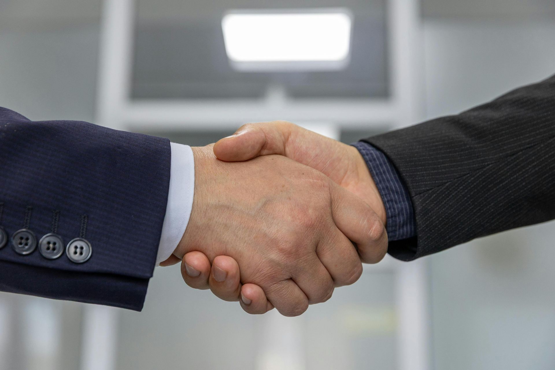 Two people in suits shaking hands in a business setting