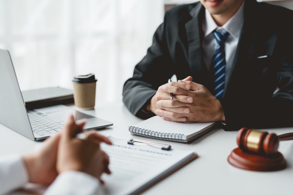 Hand signing a document on a wooden desk with a pen