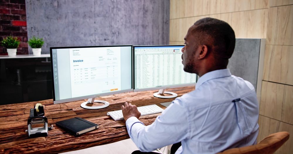 Business meeting with two people at a table, laptop, notebook, coffee cup, and gavel visible.