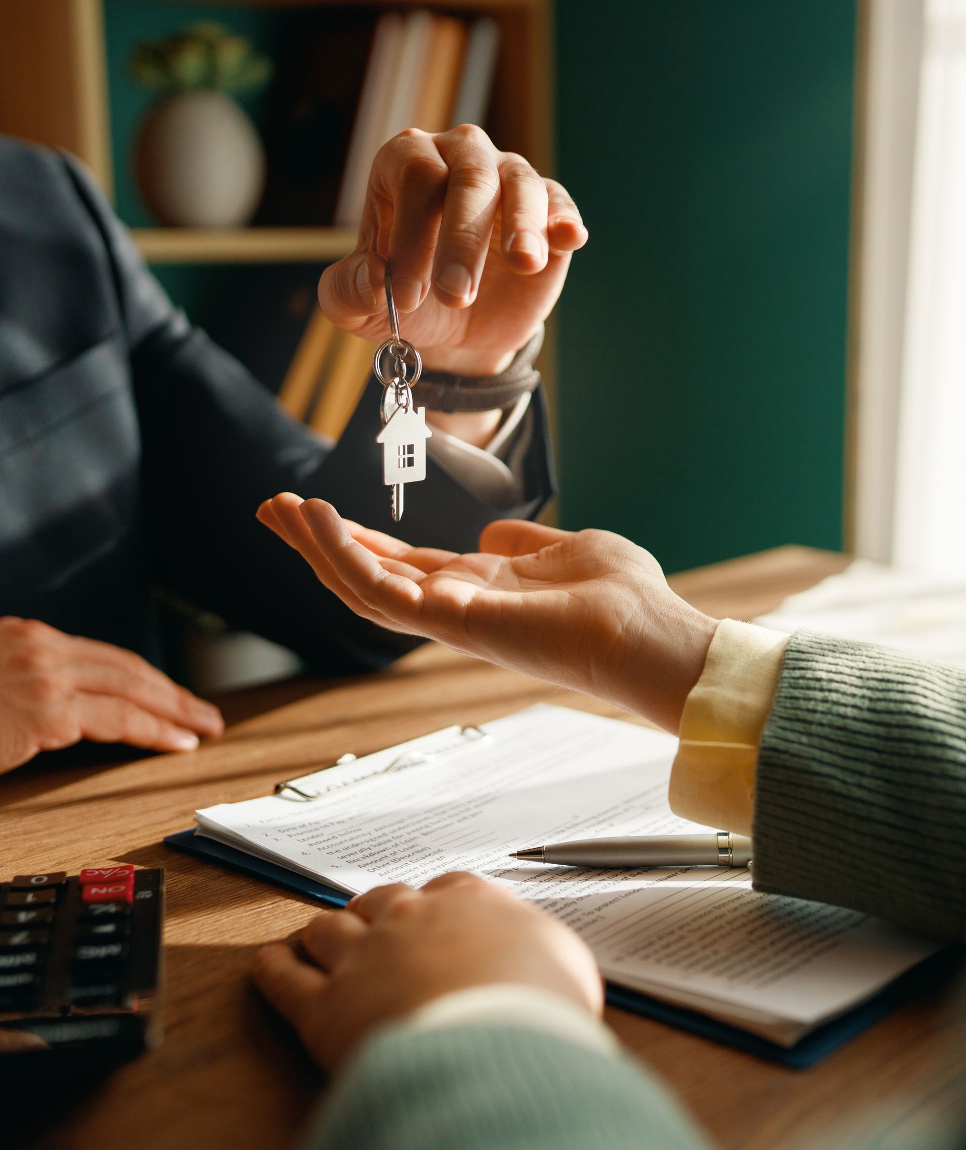 Handing over house keys above a desk during a property signing.