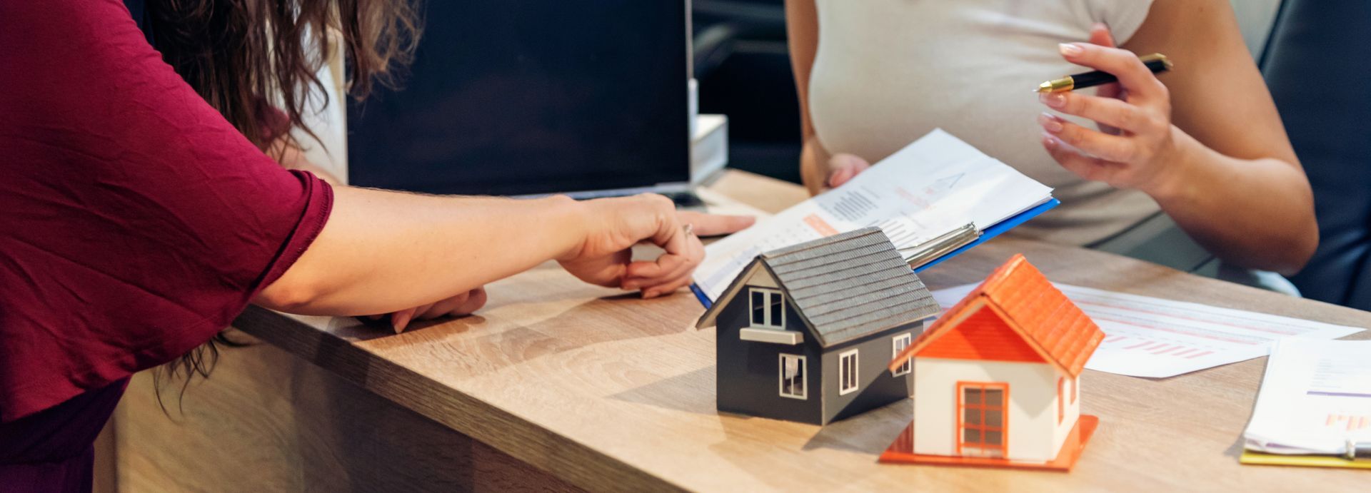 People discussing real estate models and documents at a table.
