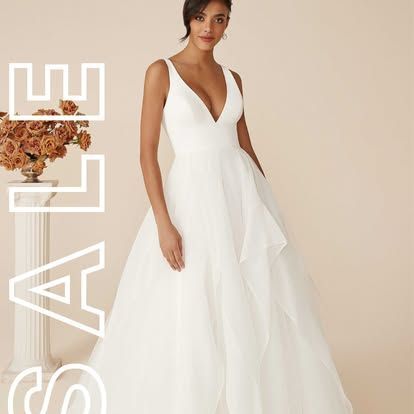 White sleeveless V-neck gown on model against beige backdrop, with vertical “ELIE” text on the left.