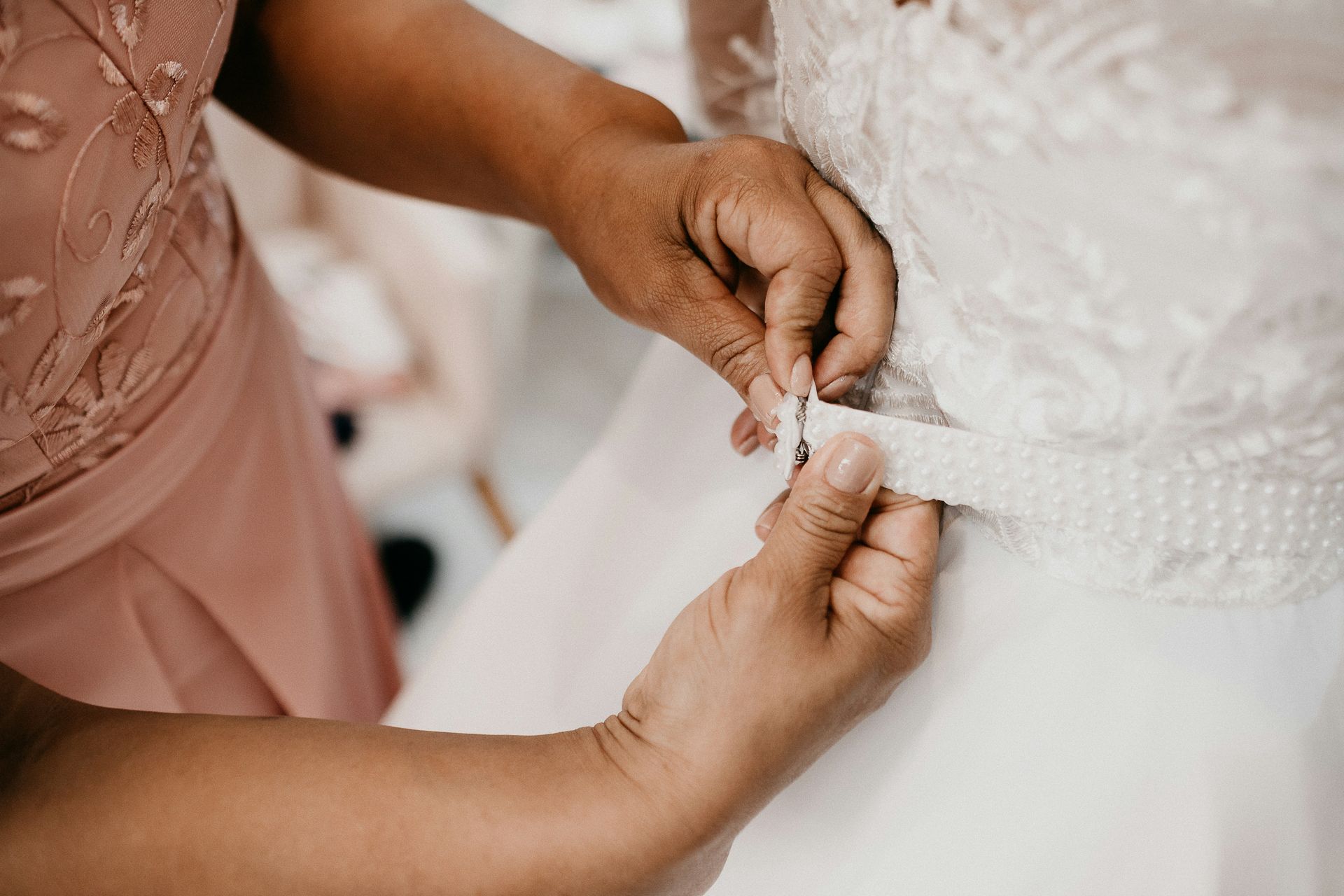 Bride getting buttoned into wedding dress