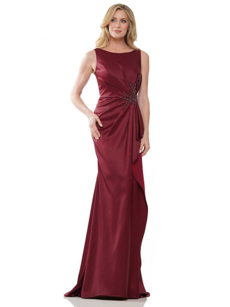 Woman in a burgundy sleeveless evening gown with draped waist detail, standing on a white background