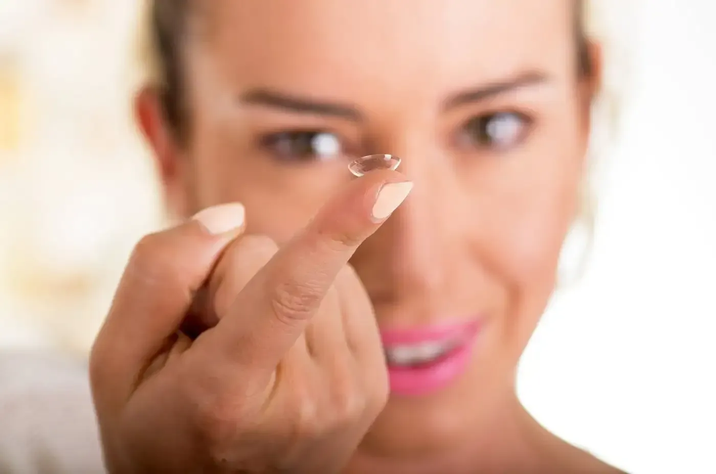 Two clear contact lenses on a wet blue surface