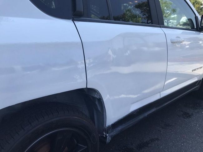 White SUV with a large dent and scratches on the side door and rear panel.