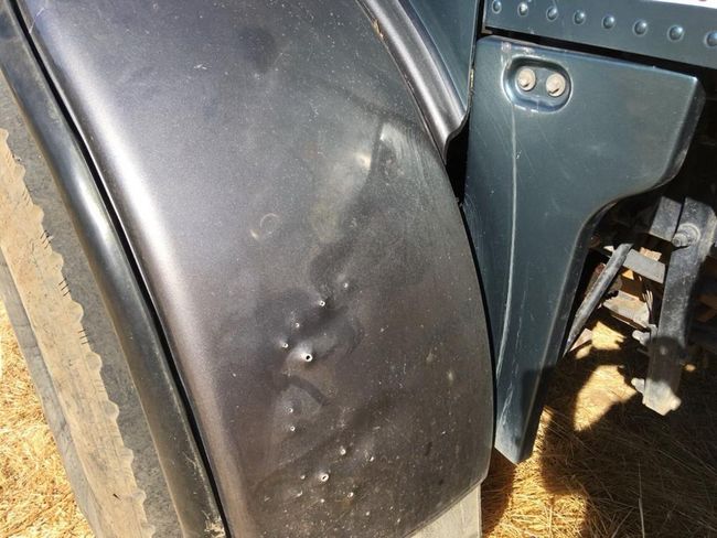 Close-up of a black vehicle fender with mud splatter and a metal bracket.