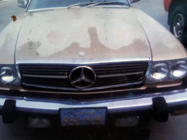 Front view of a beige Mercedes-Benz with faded hood paint parked on a street