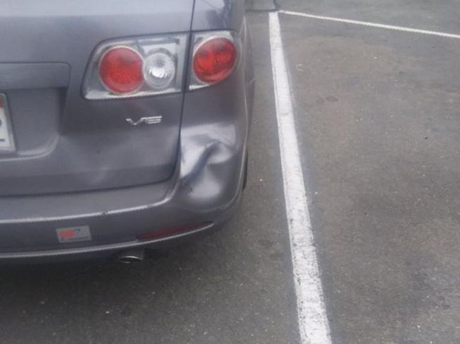 Rear view of a gray car parked beside a white line in a parking lot