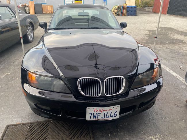Black BMW parked in a lot, front view with a damaged hood and a Utah license plate