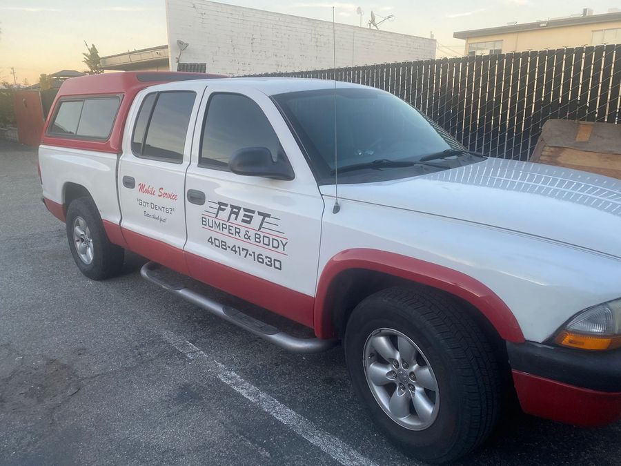 White and red service pickup truck parked in a lot at sunset