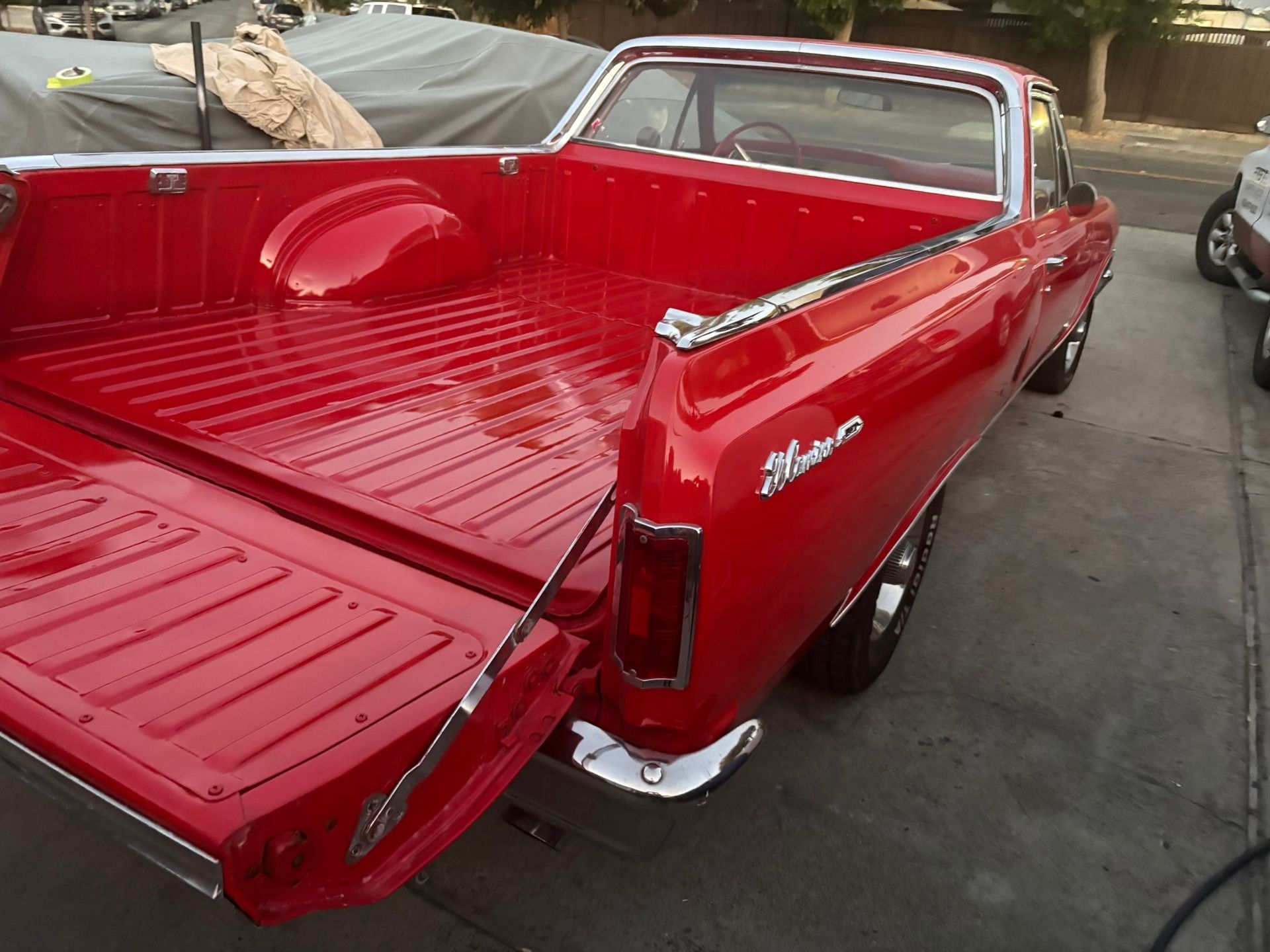 Red classic pickup truck with an empty glossy bed, parked outdoors.