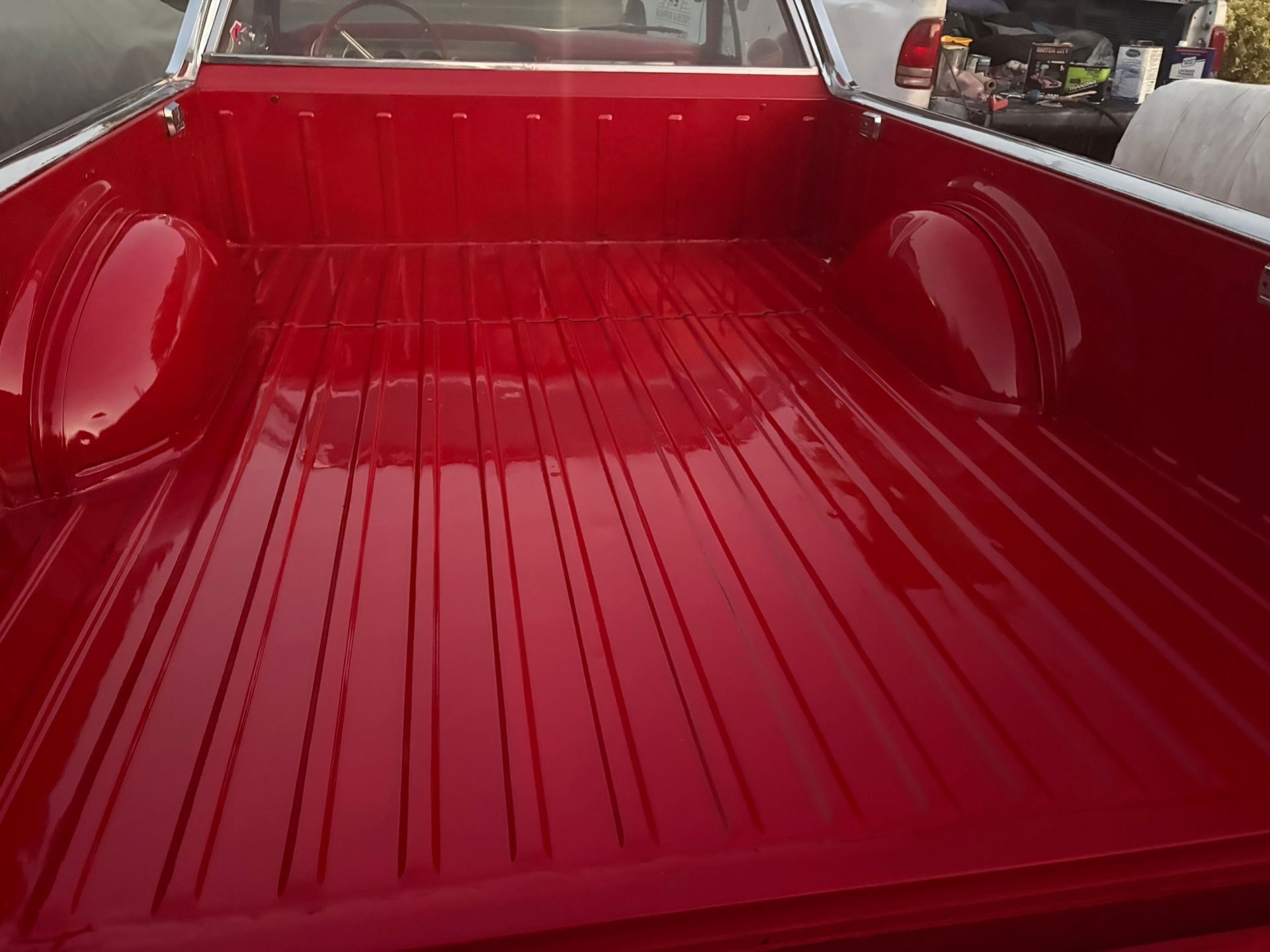 Glossy red pickup truck bed with ribbed liner, viewed from the tailgate