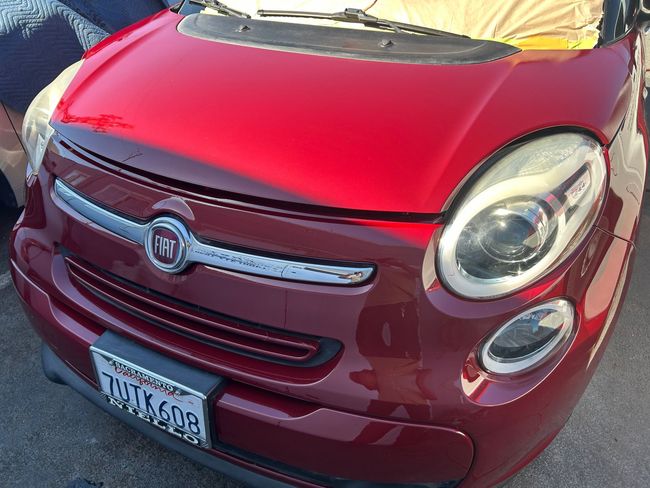 Red compact car front view in maroon with chrome grille and license plate
