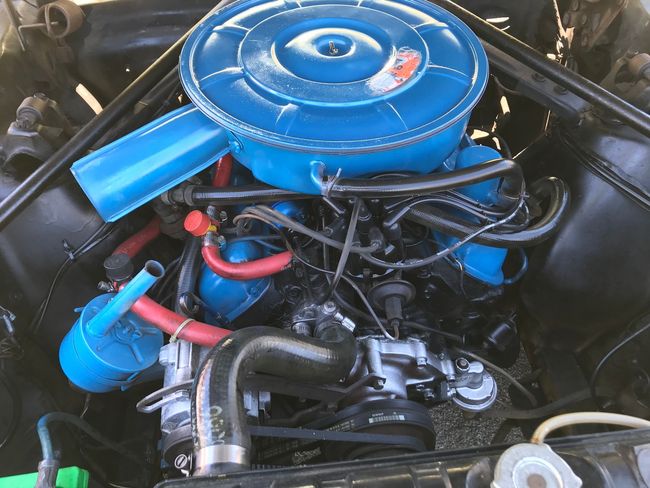 Classic car engine bay with bright blue air cleaner and hoses