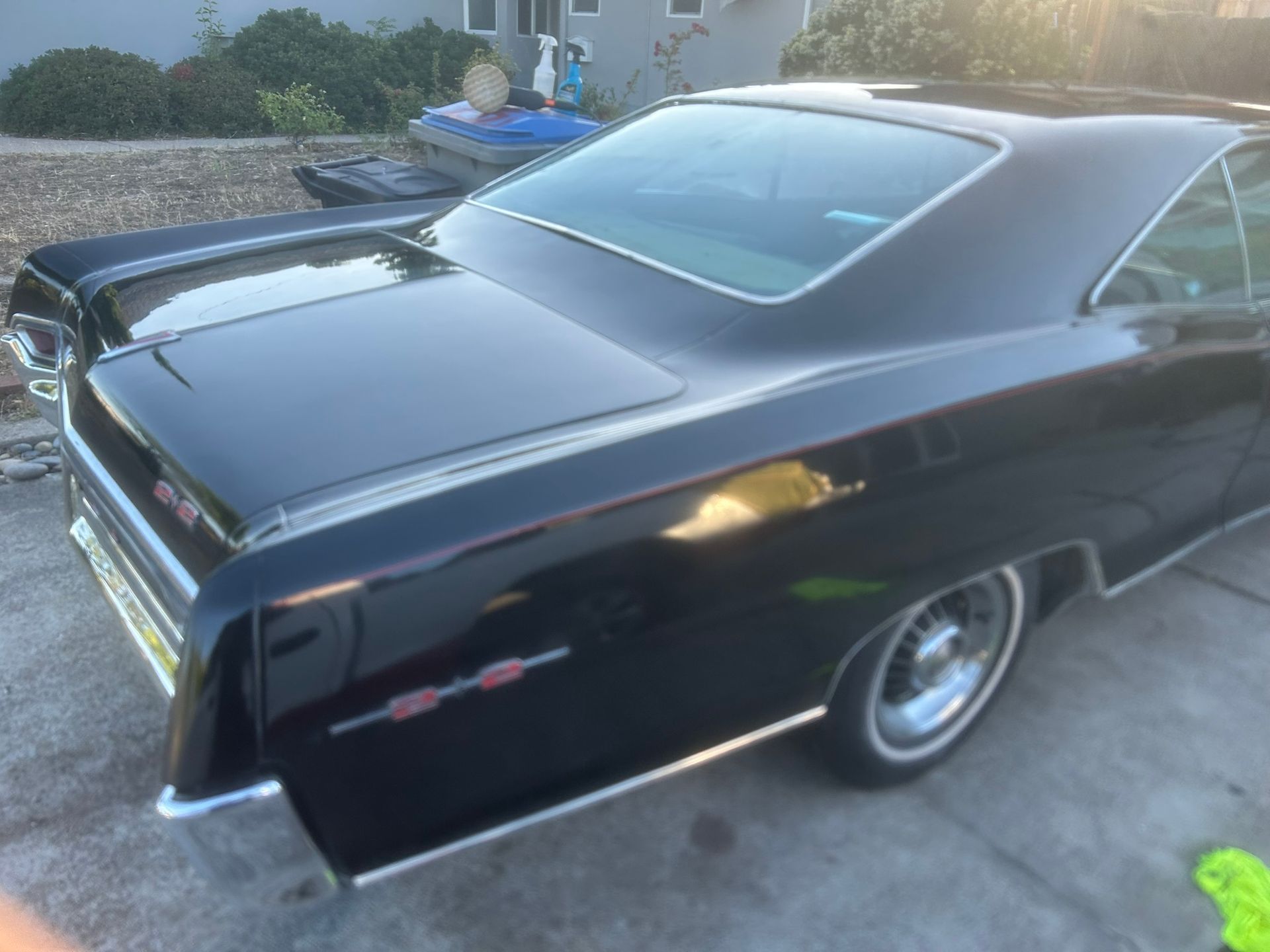 Classic black coupe parked on a driveway, seen from the rear side.